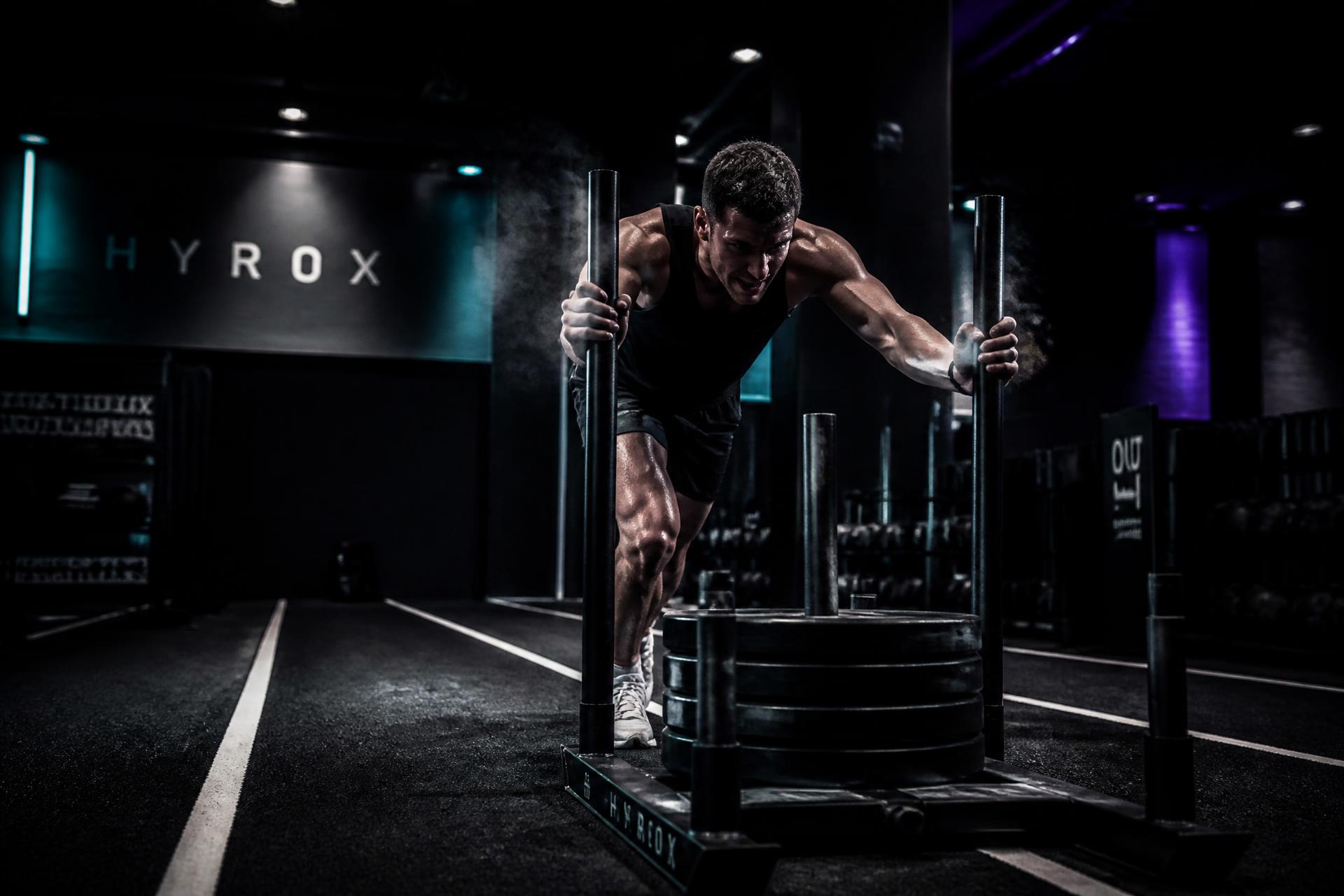 Athlete pushing a loaded sled on the HYROX training lane at RAW PRFM Fitness